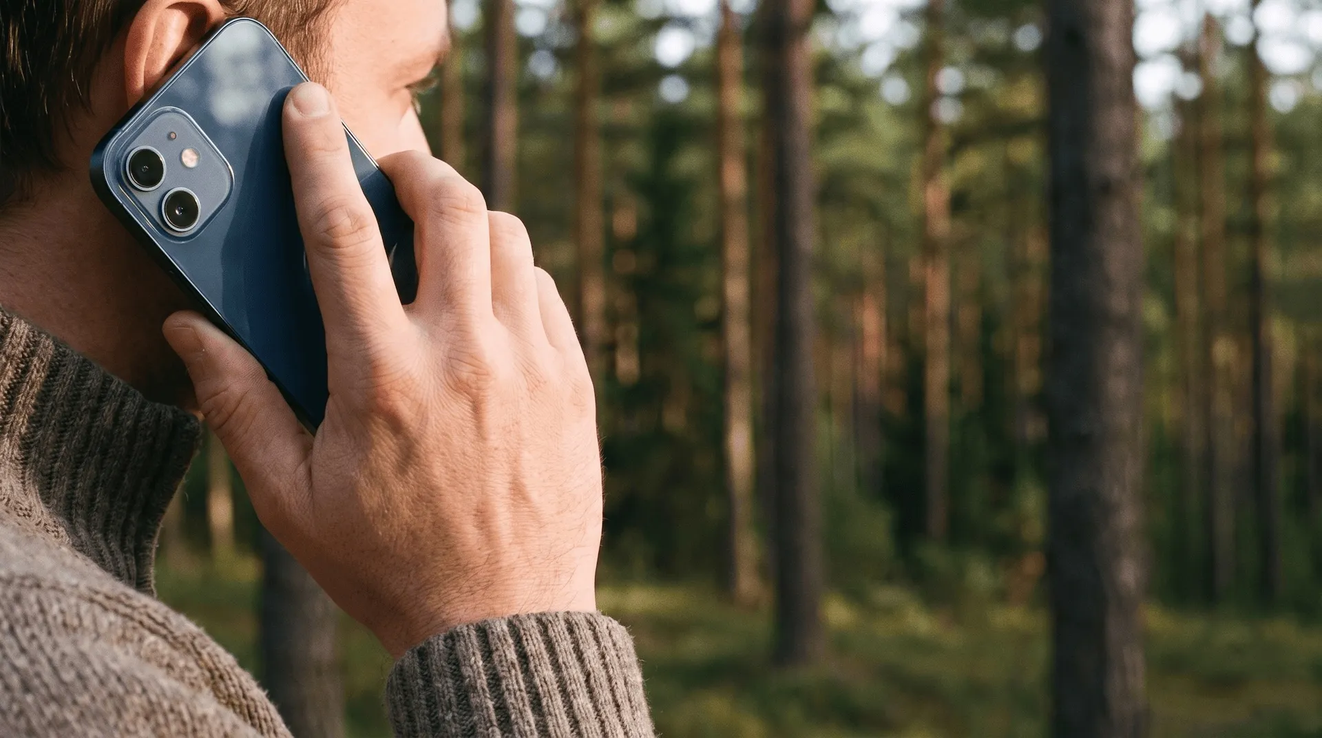 Standing Pine Media team member answering a call, pine forest in the background